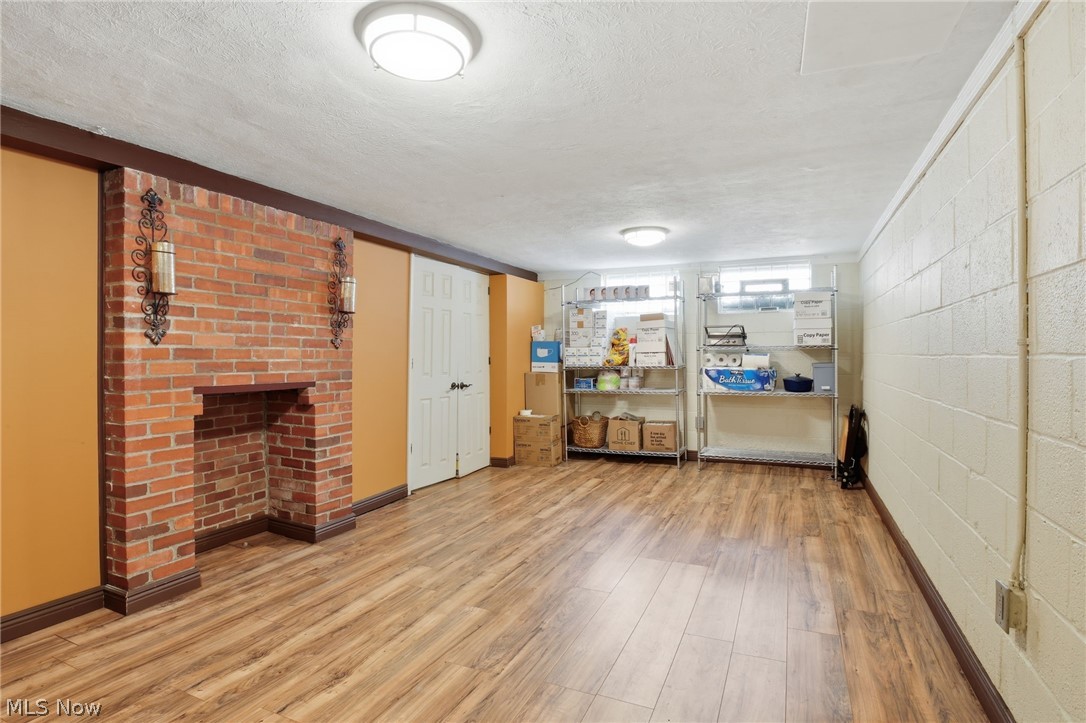 1390 Brainard Road Lyndhurst, OH 44124 - Photo 27 of 33 Below grade area with a textured ceiling, light wood-style floors, concrete block wall, and a fireplace