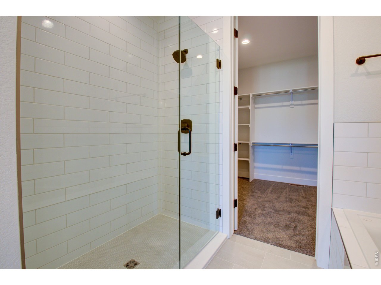 5705 2nd Road Greeley, CO 80634 - Photo 27 of 46 The primary ensuite bathroom's oversized shower with hingeless Euro shower door and full-wall surround