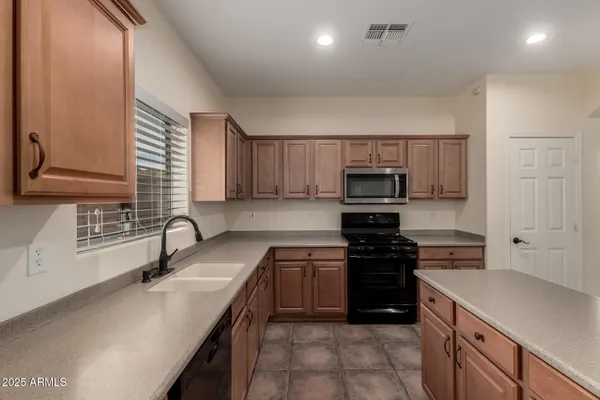 a kitchen with stainless steel appliances granite countertop a stove top oven a sink and a refrigerator