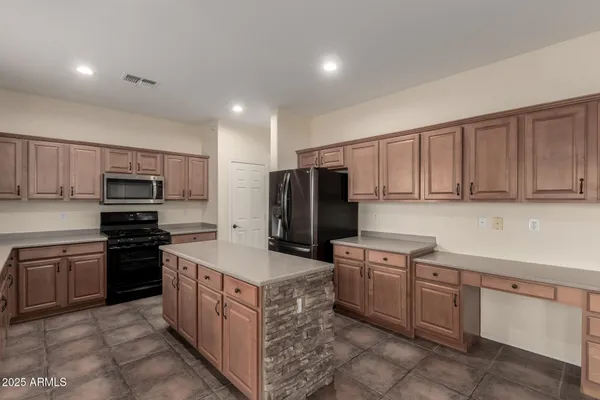 a kitchen that has a kitchen island wooden cabinets and stainless steel appliances