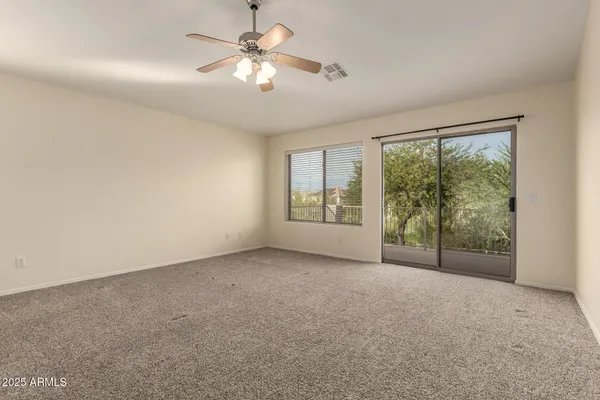 an empty room with chandelier fan and windows
