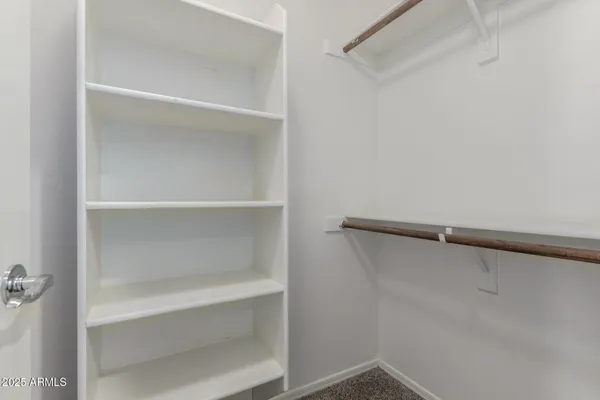 an empty room with closet and a chandelier fan