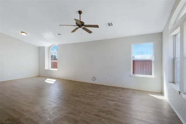 a view of empty room with wooden floor and fan