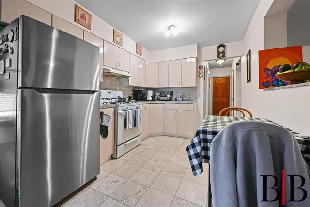 a kitchen with stainless steel appliances a refrigerator a sink a stove and white cabinets