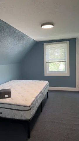 a bed sitting in a bedroom next to a window