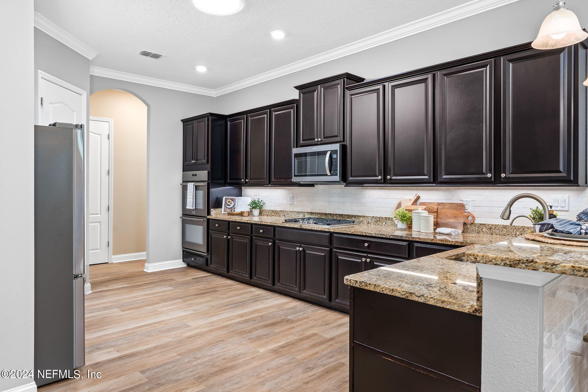 206 Medio Drive St. Augustine, FL 32095 - Photo 13 of 57 a kitchen with stainless steel appliances granite countertop wooden cabinets a refrigerator a stove a sink and dishwasher with wooden floor