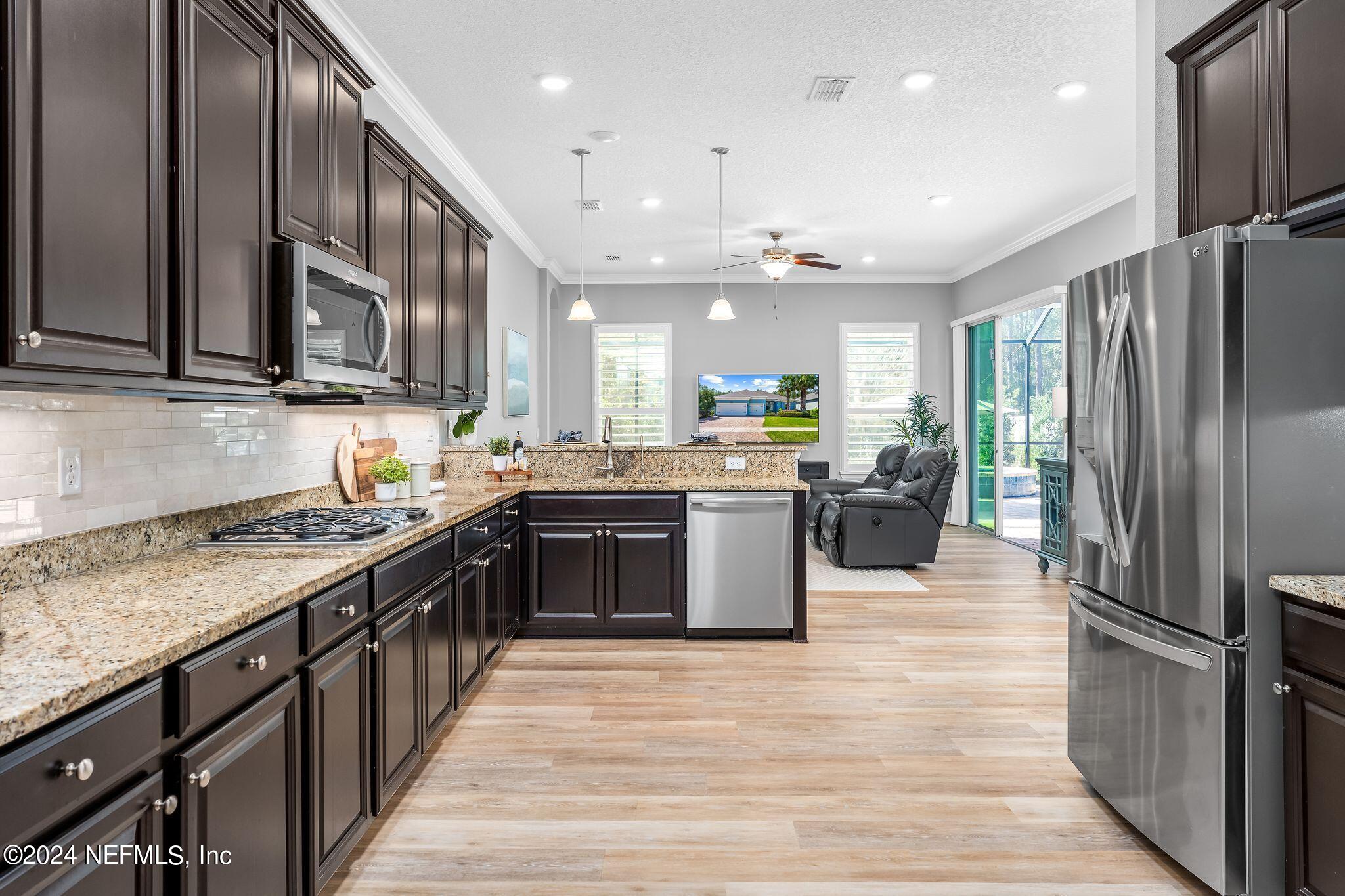 206 Medio Drive St. Augustine, FL 32095 - Photo 15 of 57 a kitchen with stainless steel appliances granite countertop a refrigerator a sink dishwasher a stove with wooden cabinets and floor