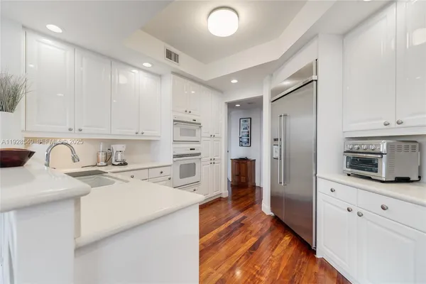 a kitchen with stainless steel appliances granite countertop a refrigerator sink and white cabinets