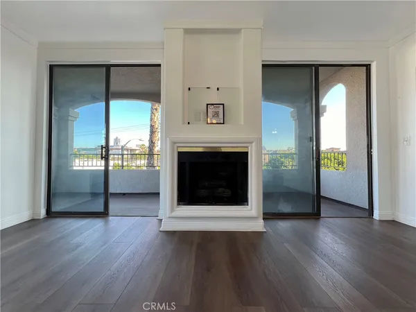 an empty room with wooden floor fireplace and windows