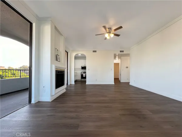 a view of an empty room with a kitchen and a window