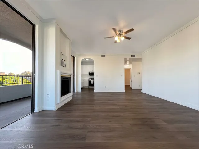 a view of an empty room with a kitchen and a window
