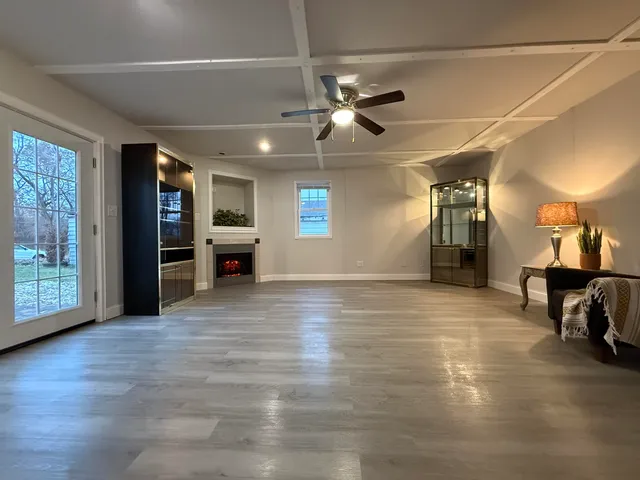 a view of an empty room with window and wooden floor