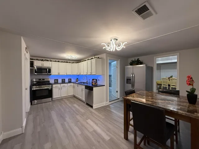 a kitchen with stainless steel appliances kitchen island granite countertop a refrigerator a stove and a wooden floors