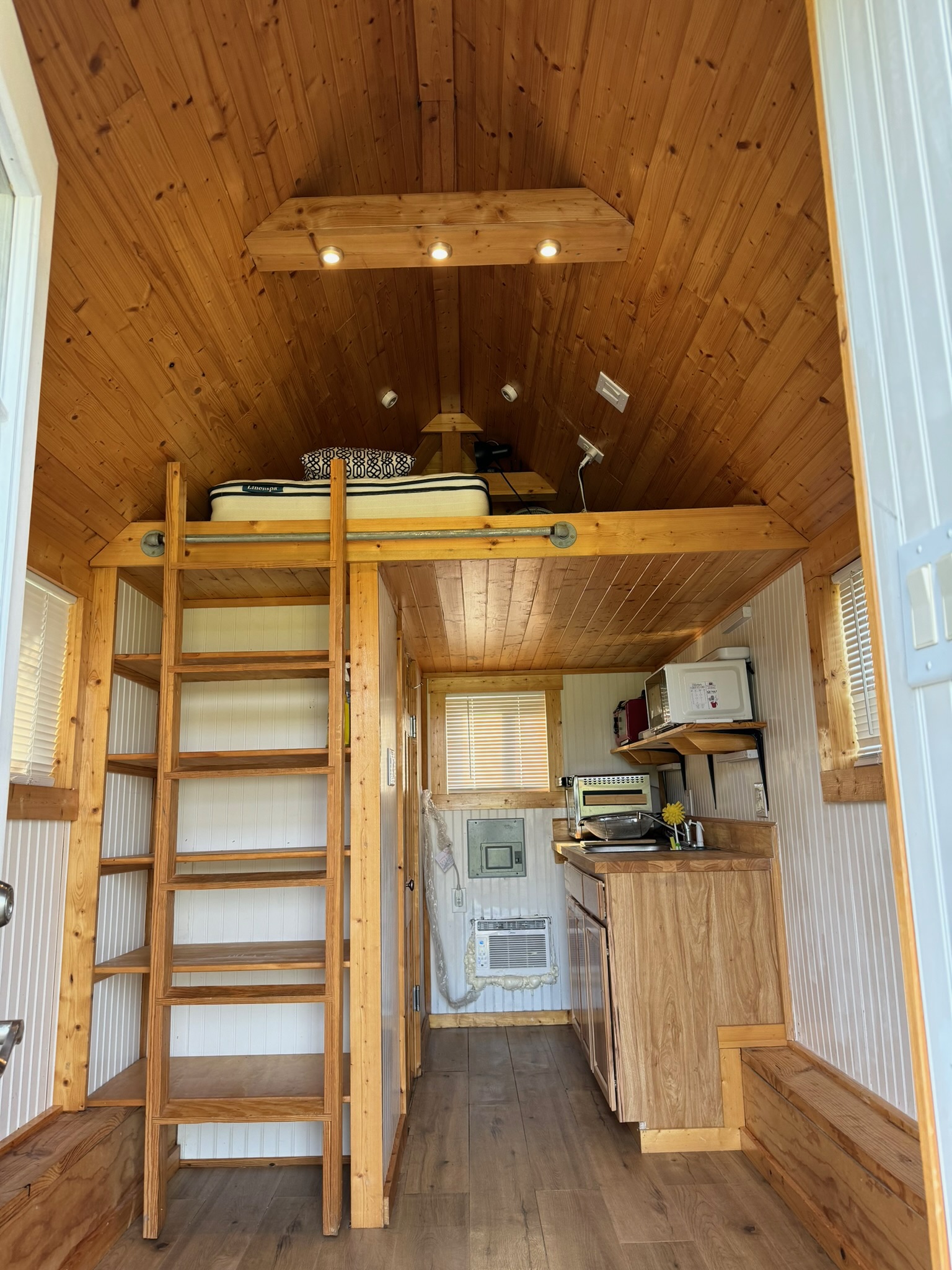 1512 River Grove Road, Unit A Kingsbury, TX 78638 - Photo 20 of 35 Kitchen with a wood ceiling with exposed beams, dark wood-style floors, wooden walls, white microwave, and light countertops