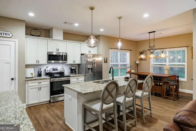 a kitchen with stainless steel appliances granite countertop a kitchen island hardwood floor sink stove dining table and chairs