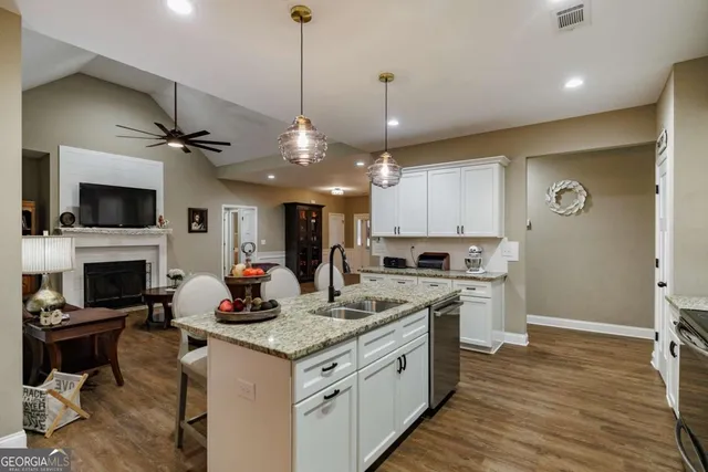a open kitchen with stainless steel appliances granite countertop a stove refrigerator and a fireplace with wooden floor