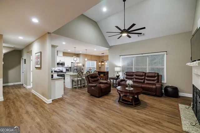 a living room with furniture a wooden floor and a ceiling fan
