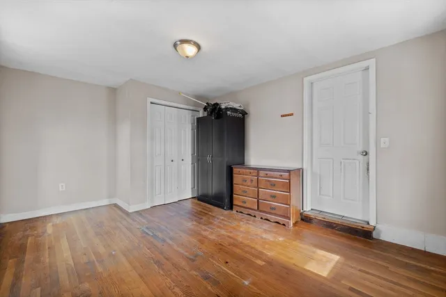 an empty room with wooden floor and cabinet