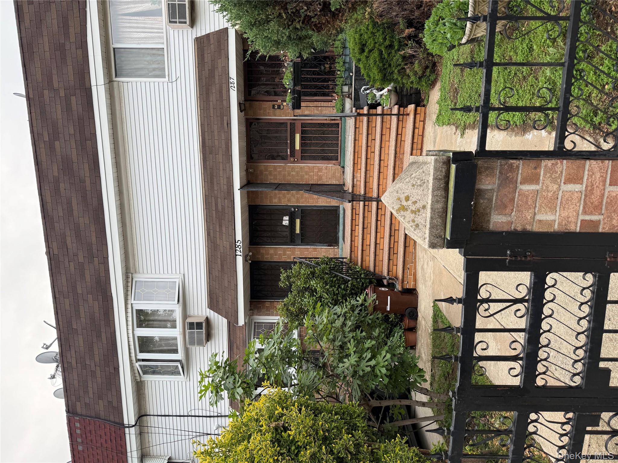 View of front of home featuring a shingled roof, a gate, mansard roof, and a fenced front yard