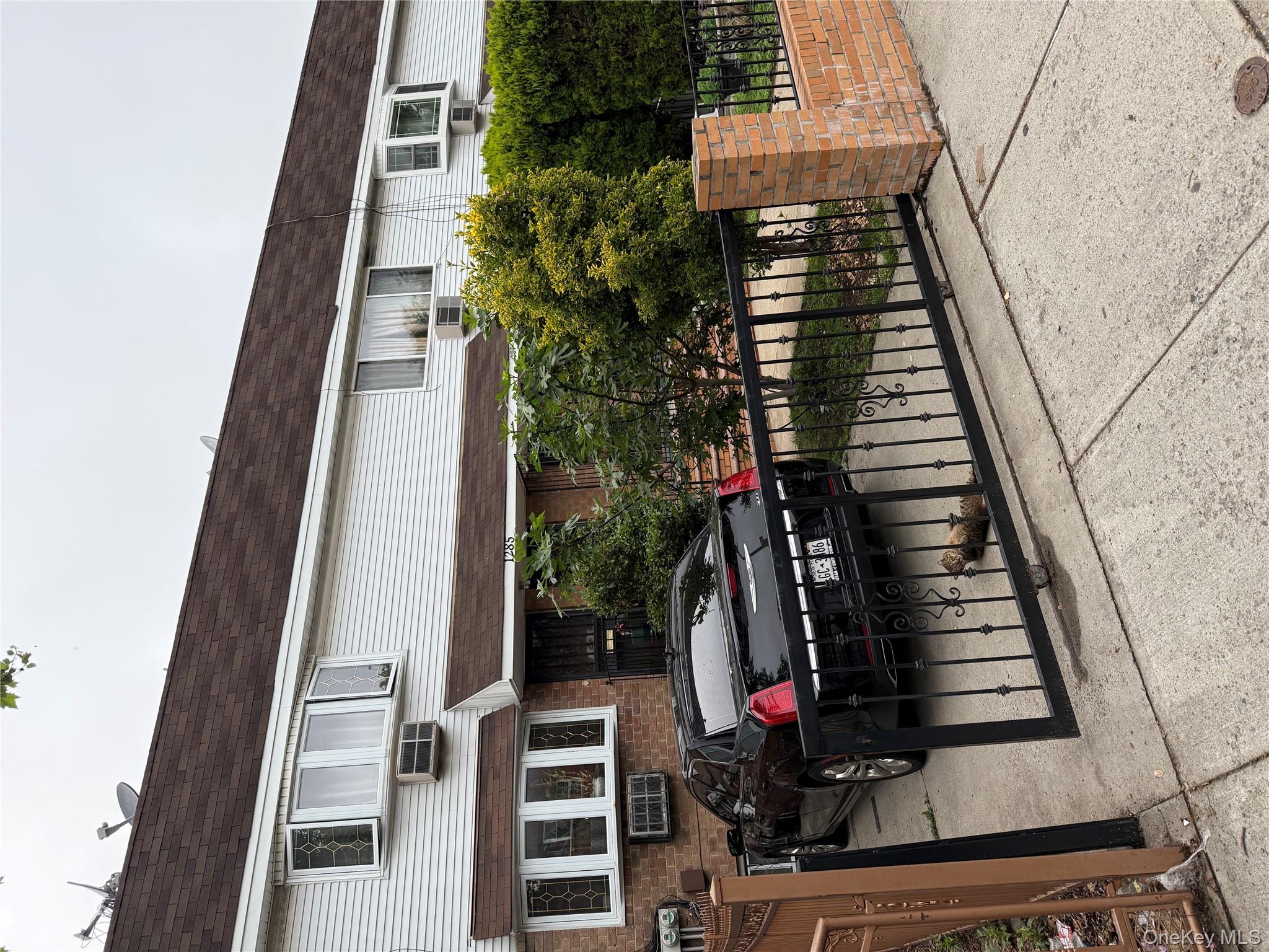 1285 Putnam Avenue Brooklyn, NY 11221 - Photo 2 of 8 View of front of home with a shingled roof, brick siding, a gate, and mansard roof