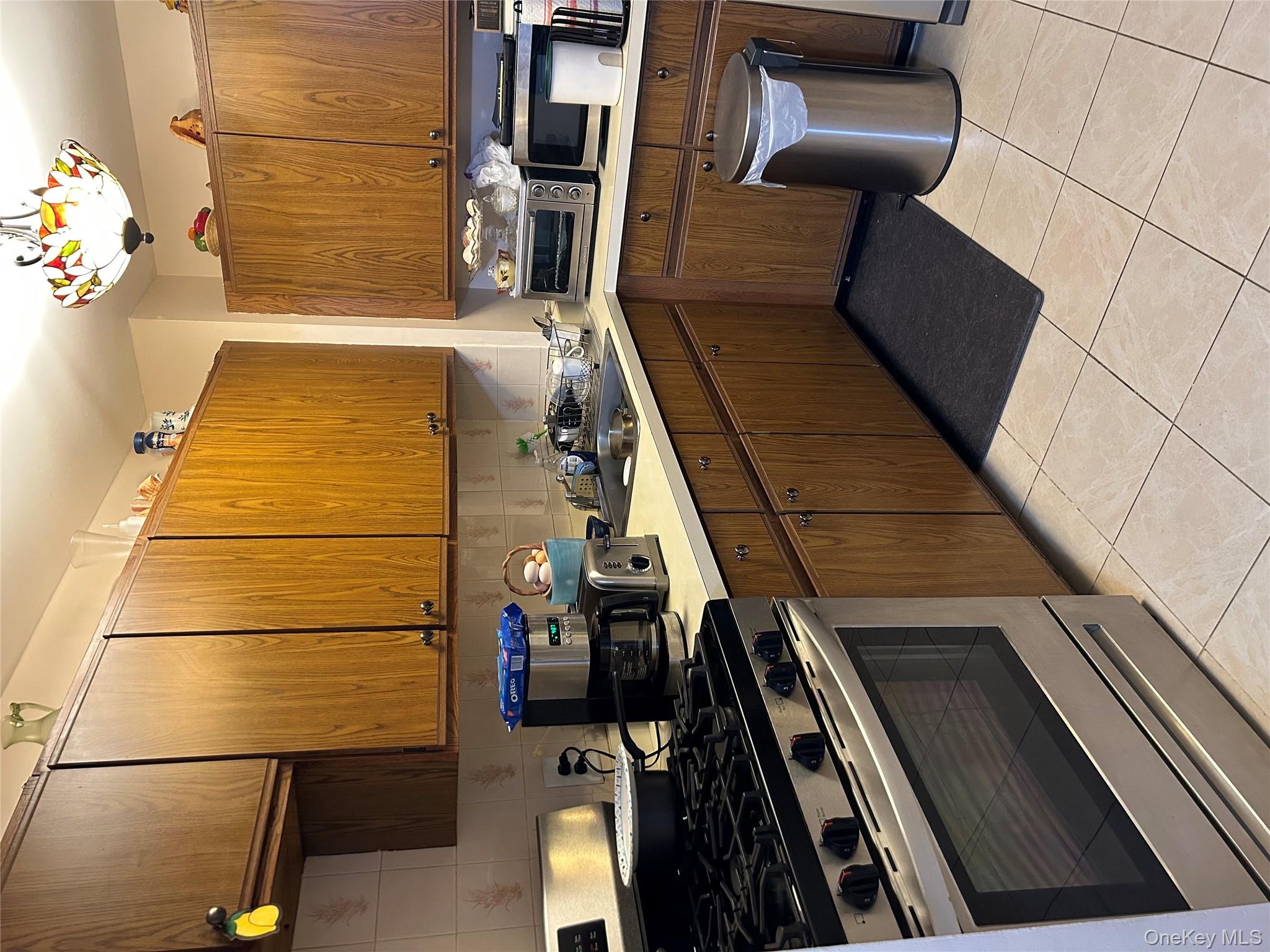 1285 Putnam Avenue Brooklyn, NY 11221 - Photo 6 of 8 Kitchen with stove, decorative backsplash, light countertops, light tile patterned floors, and hanging light fixtures