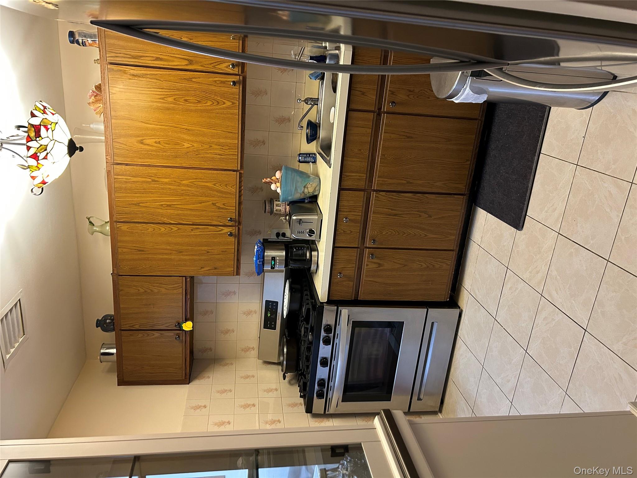 1285 Putnam Avenue Brooklyn, NY 11221 - Photo 8 of 8 Kitchen with tasteful backsplash, range, light countertops, and light tile patterned floors