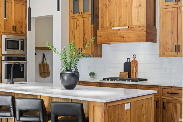 2197 Reserve Circle St. George, UT 84770 - Photo 16 of 57 Kitchen with glass insert cabinets, wood finish cabinetry, stainless steel appliances, a breakfast bar area, and tasteful backsplash