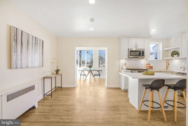 a kitchen with stainless steel appliances granite countertop a stove a sink a refrigerator and white cabinets with wooden floor