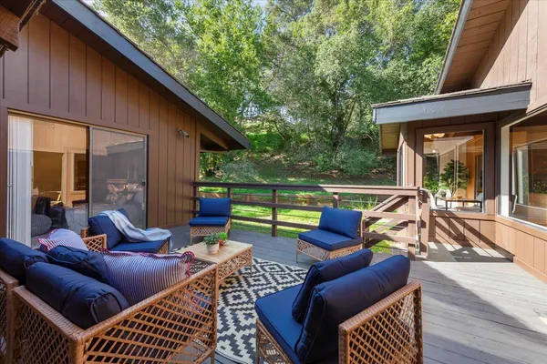a view of a patio with couches and table and chairs with wooden floor and fence