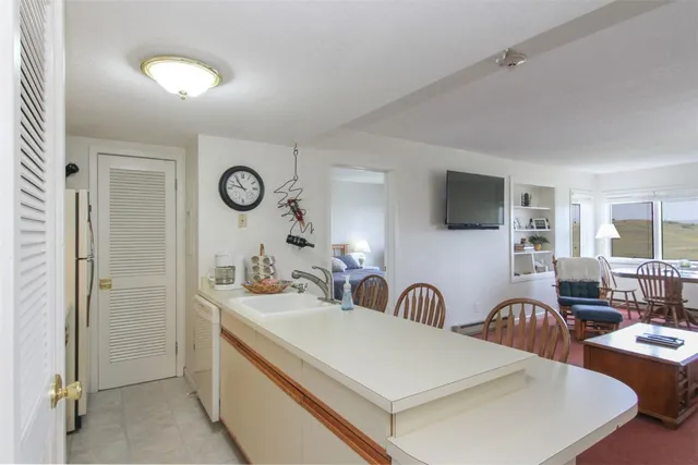 a view of a kitchen with a sink dishwasher a dining table and chairs with wooden floor