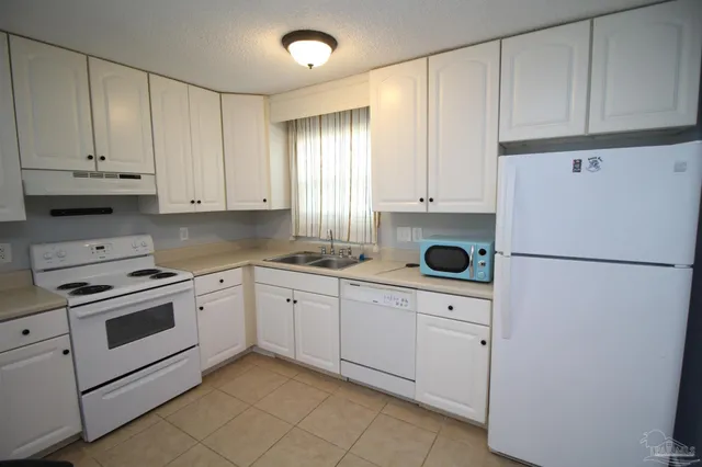 a kitchen with white cabinets and white appliances