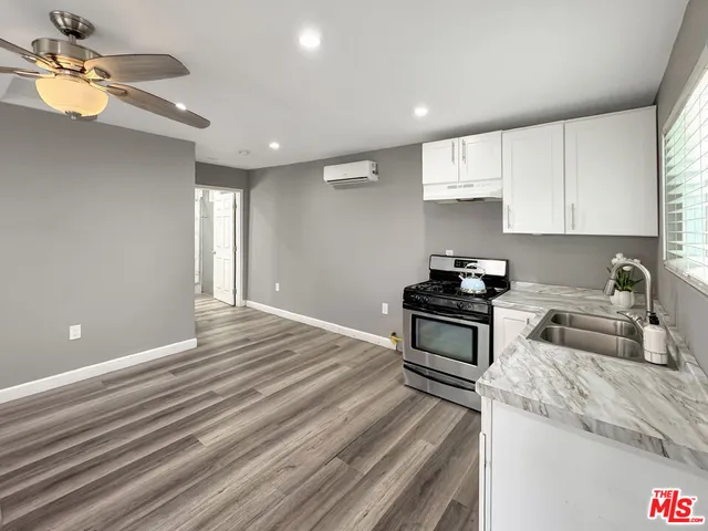 a kitchen with granite countertop a stove cabinets and wooden floor