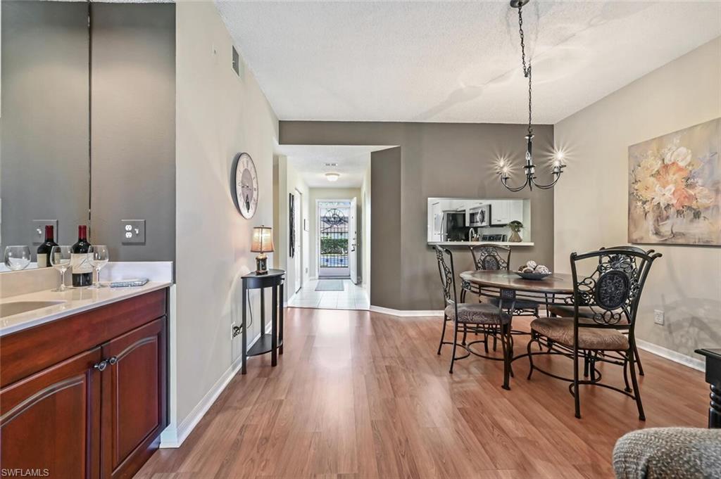565 Augusta Boulevard, Unit 24 Naples, FL 34113 - Photo 24 of 26 a view of a dining room and livingroom with furniture wooden floor a chandelier
