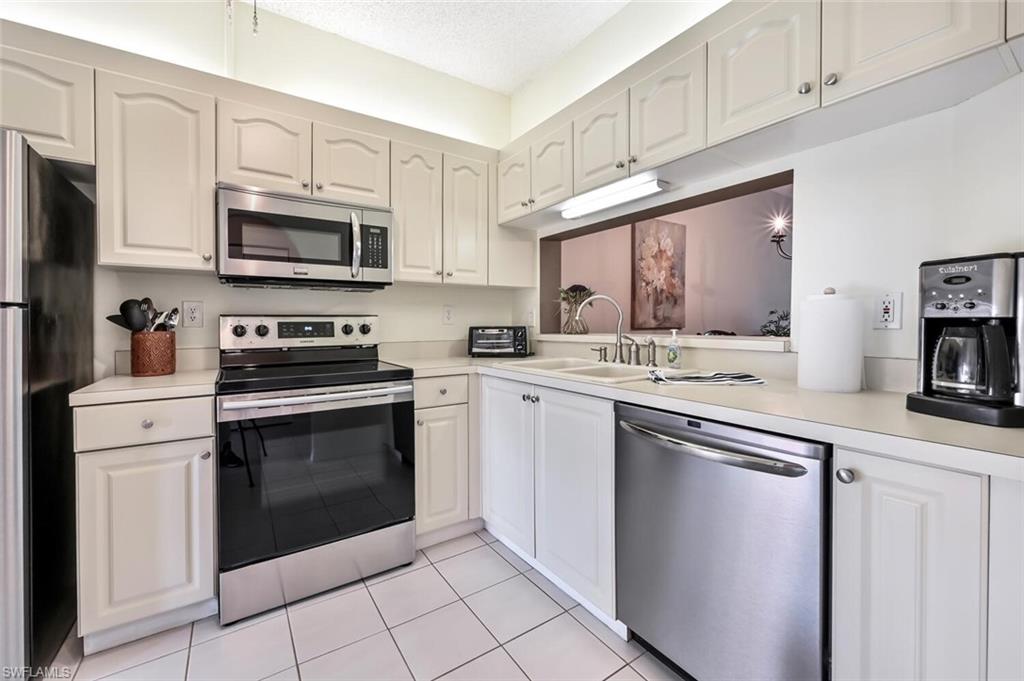 565 Augusta Boulevard, Unit 24 Naples, FL 34113 - Photo 4 of 26 a kitchen with cabinets stainless steel appliances and a sink