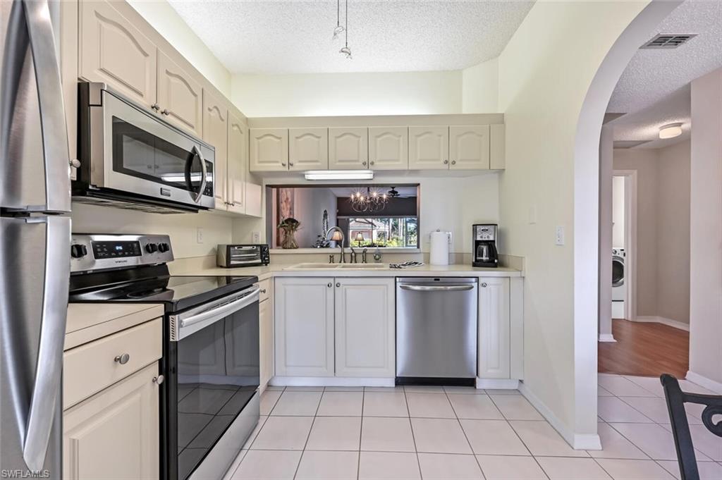 565 Augusta Boulevard, Unit 24 Naples, FL 34113 - Photo 8 of 26 a kitchen with white cabinets and appliances