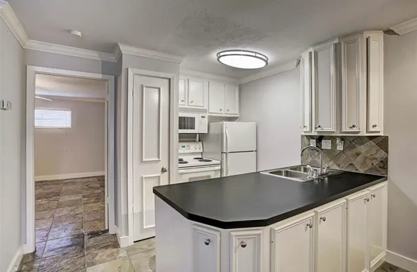 a kitchen with granite countertop a sink a refrigerator and cabinets