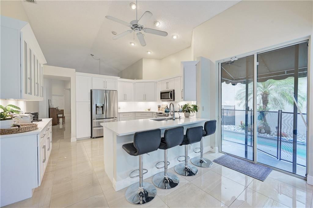 8171 Hampton Wood Drive Boca Raton, FL 33433 - Photo 55 of 56 a large kitchen with kitchen island a large counter space a sink appliances and cabinets