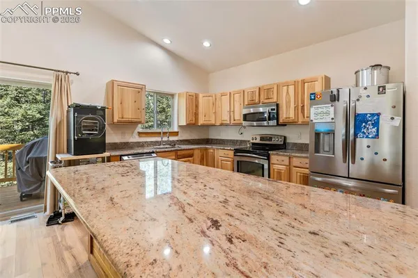 a kitchen with stainless steel appliances granite countertop a stove top oven a sink a dining table and chairs