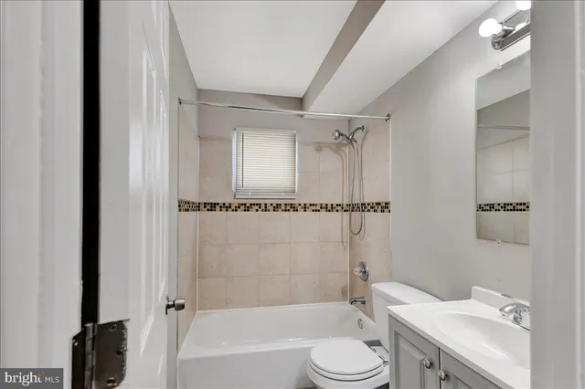 a bathroom with a granite countertop bathtub shower sink vanity and toilet