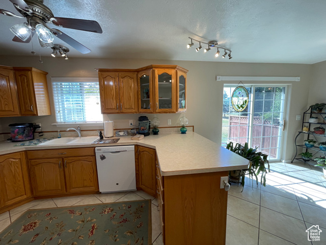 11473 South Dempsey Creek Road Lava Hot Springs, ID 83246 - Photo 10 of 47 Kitchen featuring a peninsula, light tile patterned flooring, dishwasher, a textured ceiling, and brown cabinets