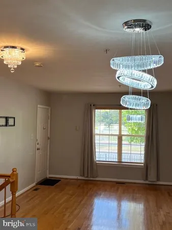 an empty room with wooden floor chandelier and windows