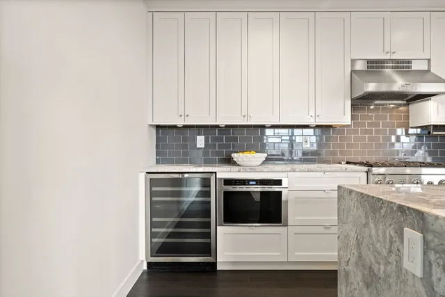 a kitchen with stainless steel appliances a stove and white cabinets