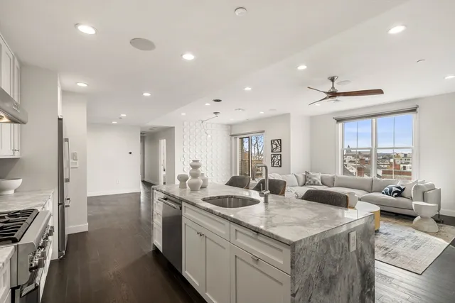 a large kitchen with kitchen island a large counter top space a sink stainless steel appliances and windows