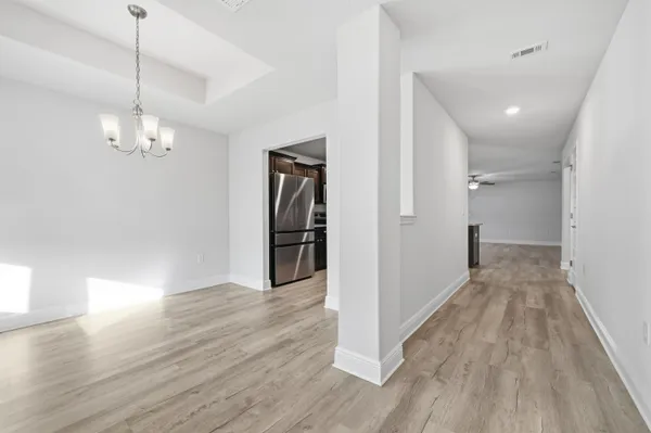 a view of a hallway with wooden floor and chandelier