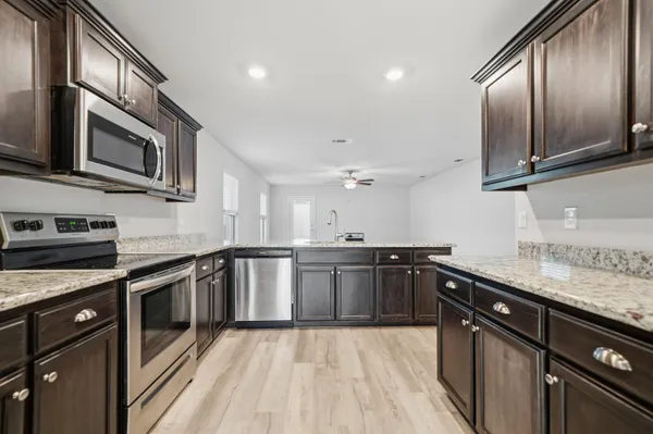 a kitchen with stainless steel appliances granite countertop a sink a stove top oven and wooden floor
