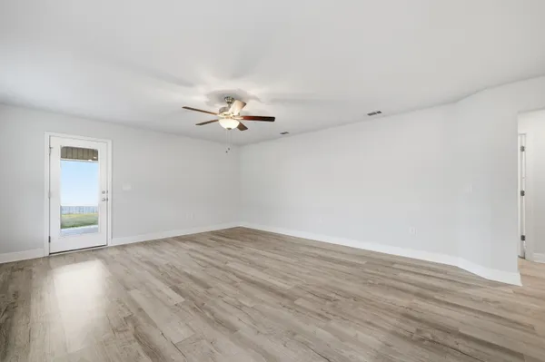 an empty room with wooden floor and chandelier fan