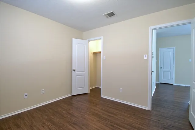a view of an empty room with wooden floor and closet
