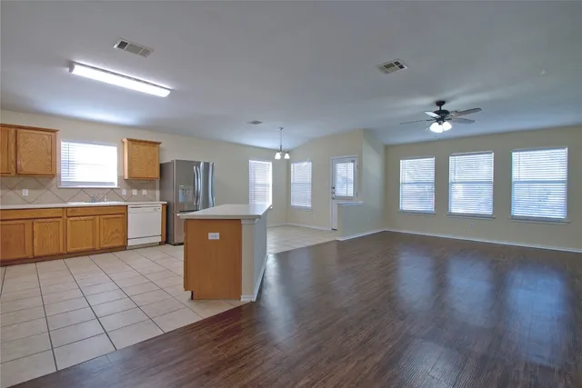 a view of an empty room with a kitchen and a window