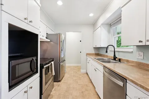 a kitchen with stainless steel appliances granite countertop a sink and a refrigerator
