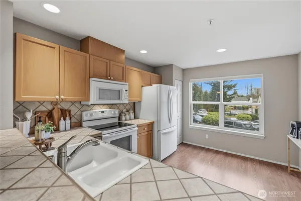 a kitchen with a refrigerator a stove top oven and white cabinets